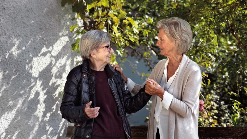 Zwei Seniorinnen begrüssen sich.