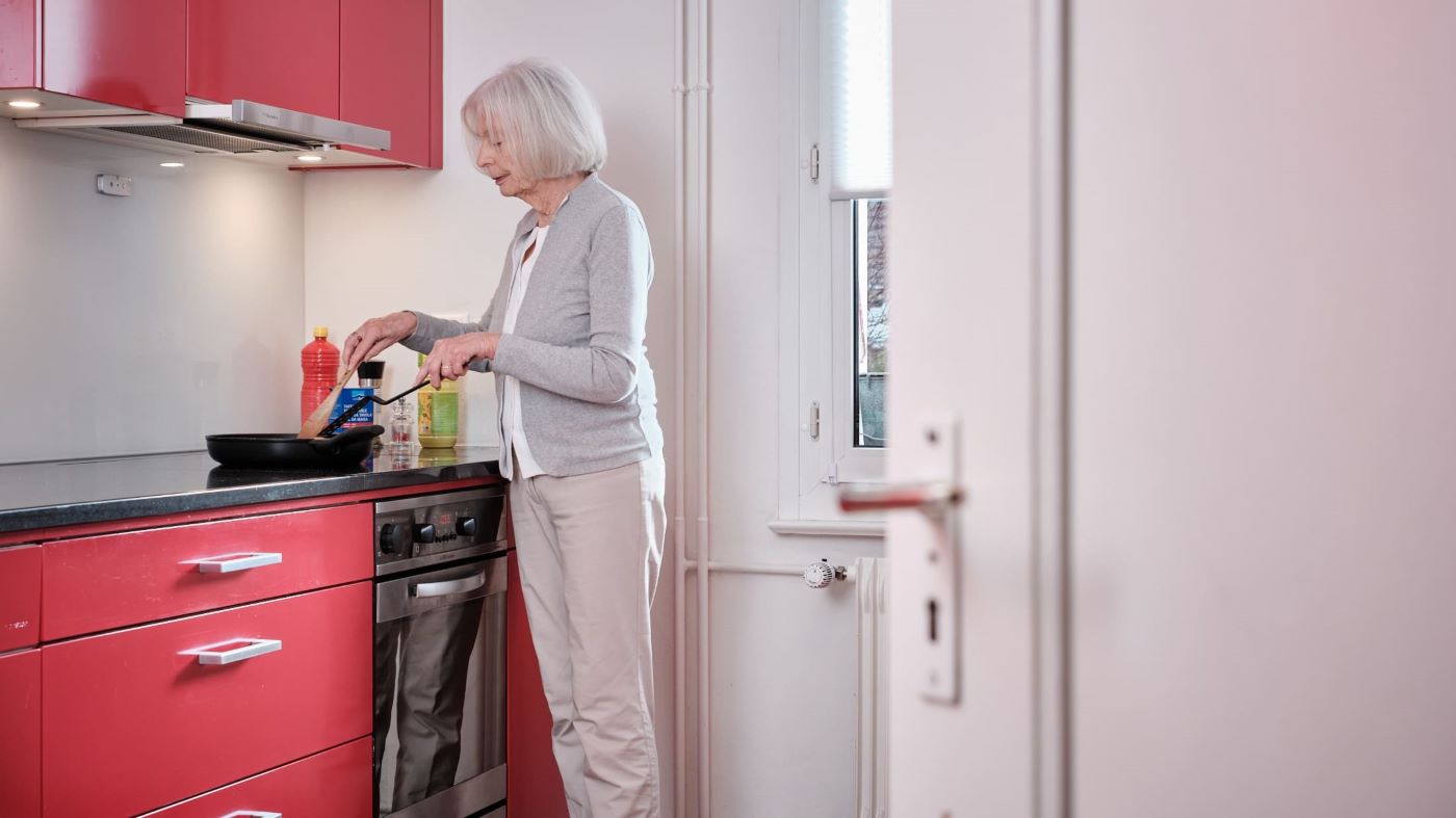 Una donna anziana è in cucina a cucinare.